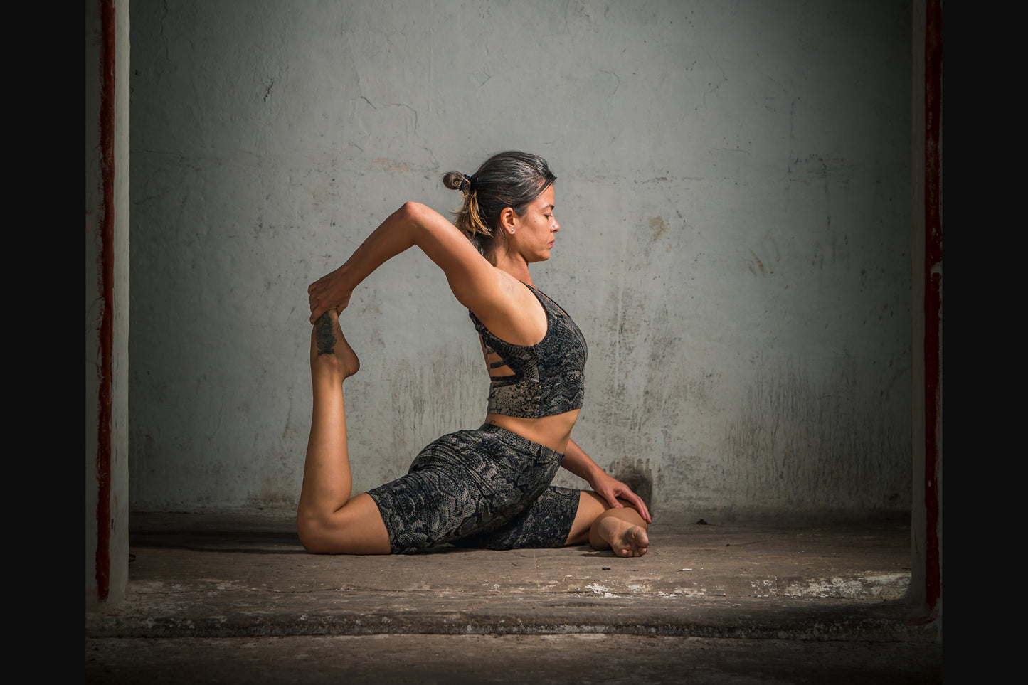 Frau in Yoga Pose trägt Batik Schlangenprint Stretch Fitness Shorts Shorts schwarz-grau-beige – Workout Wear, Alternative Mode