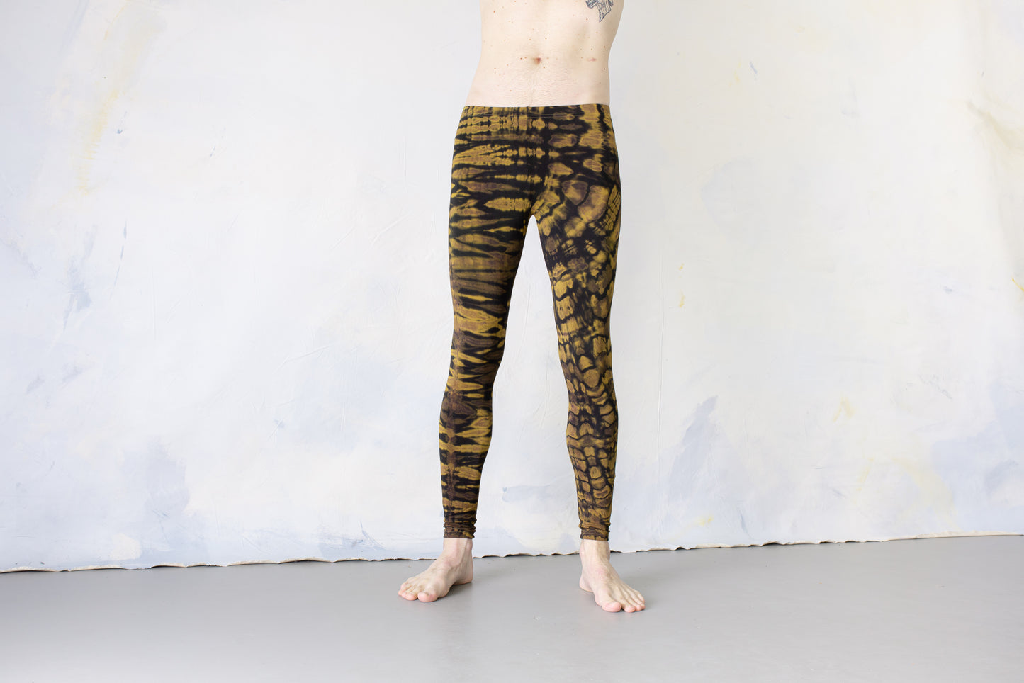 Mann trägt elastische Unisex Batik Tigerprint Leggings schwarz-beige-gelb – Yoga Psytrance Punk Alternative Mode Festival Style