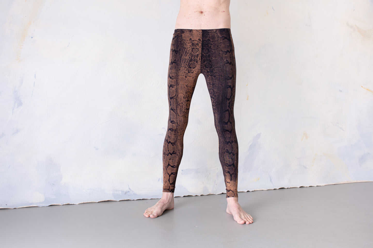 Mann trägt Unisex Batik Leggings mit Schlangenmuster, Animal Print rostbraun-orange – Yoga, Psytrance & Alternative Fashion