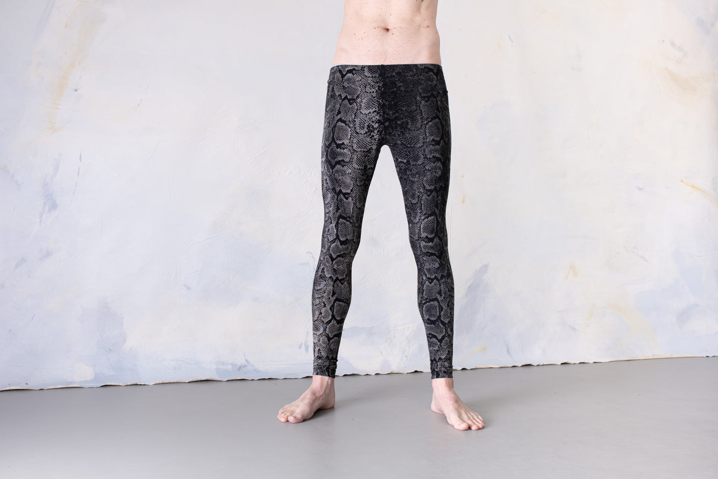 Mann trägt Unisex Batik Leggings mit Schlangenmuster, Animal Print schwarz-grau-weiß – Yoga, Psytrance & Alternative Fashion