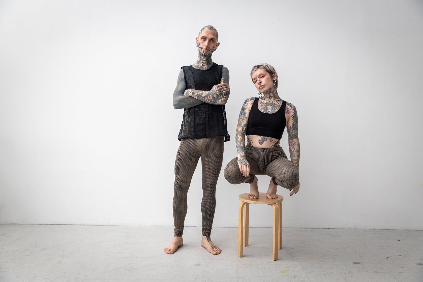 Alternative Models tragen genderneutrale Leggings mit ausgefallenem Druck in beige-blau.