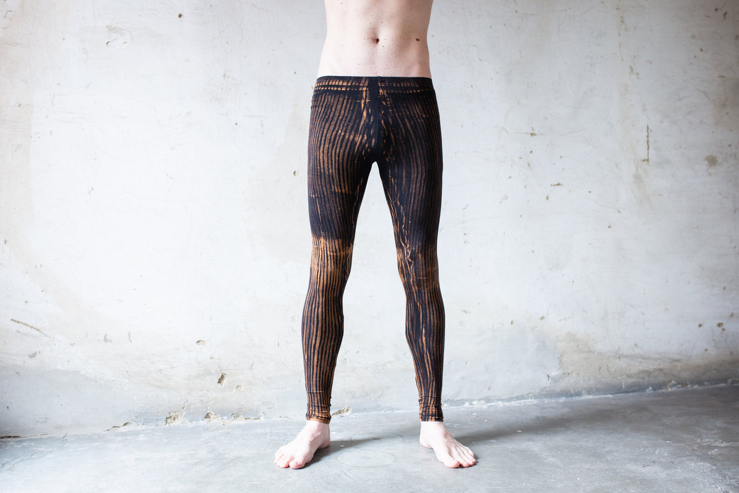 Mann trägt Unisex Viskose Batik Leggings mit Streifenmuster schwarz-apricot – Yoga, Psytrance & Alternative Fashion