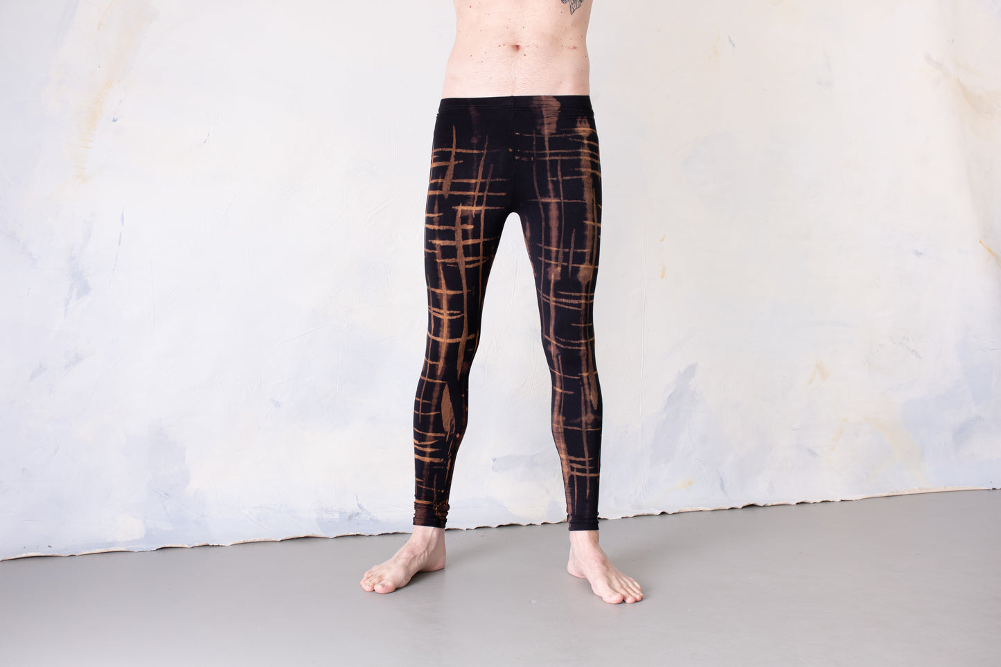 Mann trägt Unisex Batik Leggings mit abstraktem Punk-Scribble Print schwarz-braun-apricot – Alt Fashion Yoga Psytrance Punk Goa