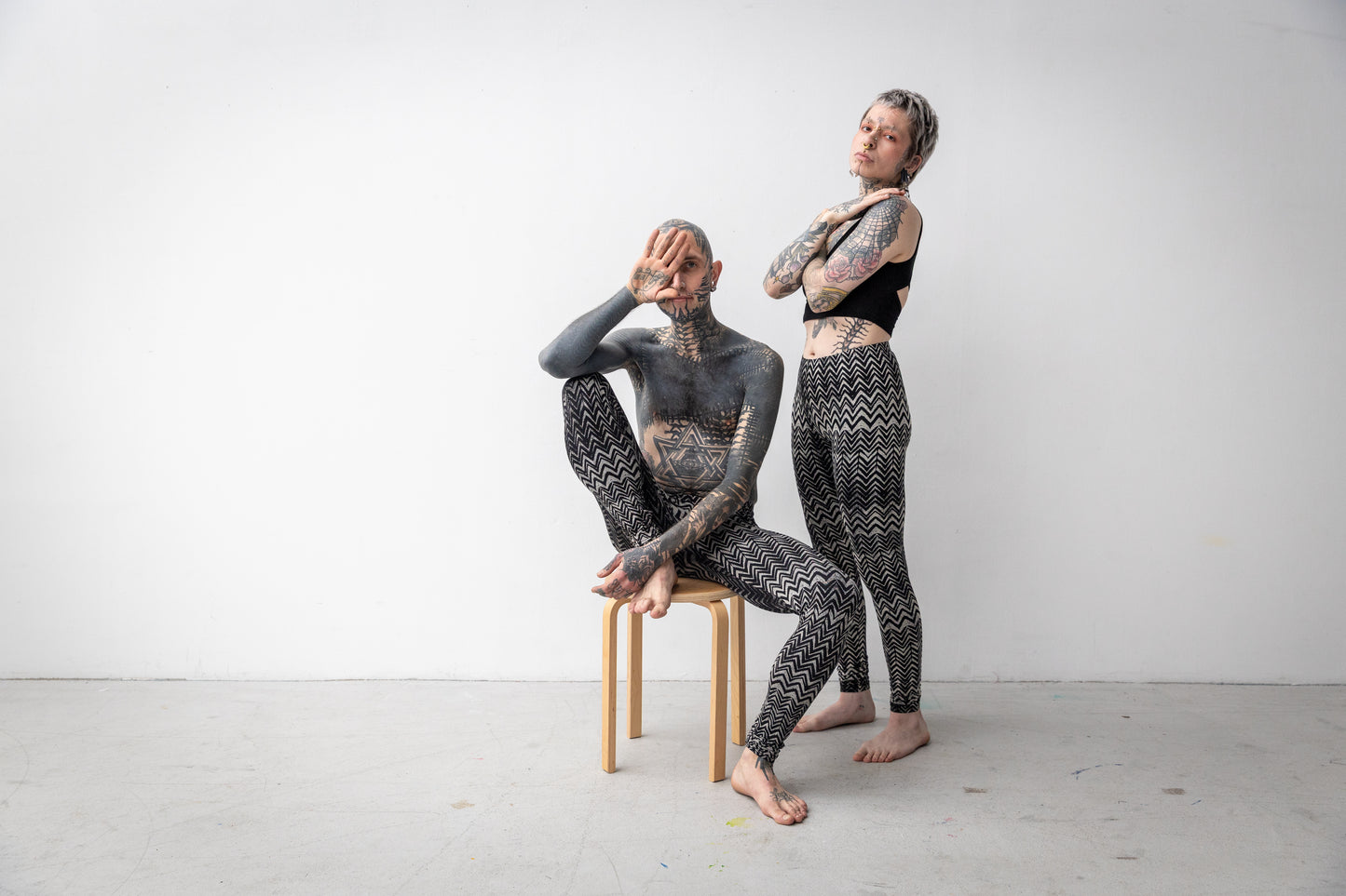 Unisex Leggings mit abstraktem Wellenmuster in schwarz-beige-grau, getragen an zwei ausdrucksstarken Models.