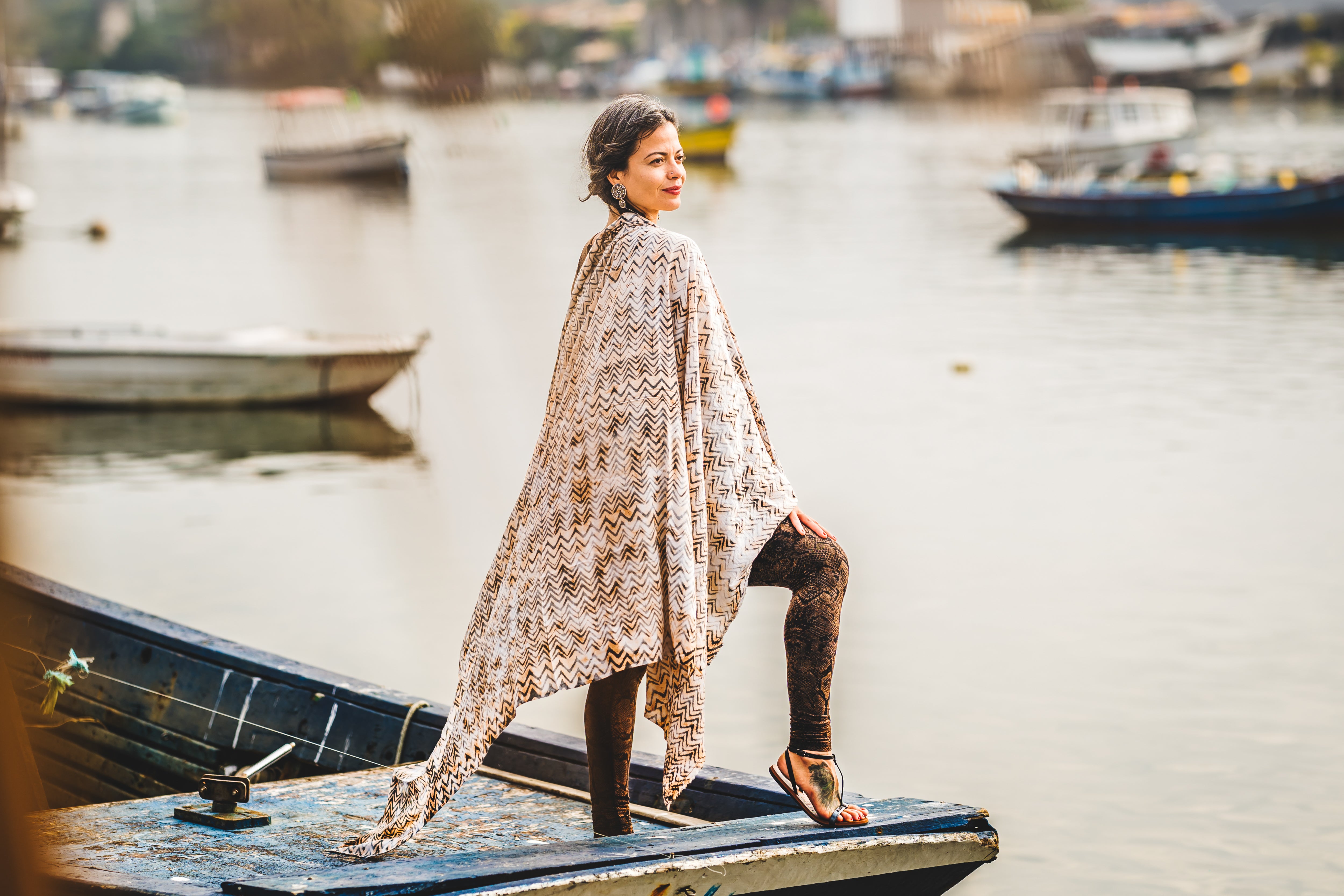 Frau auf einem Boot im Hafen trägt einen terracottafarbenen großen Viskose-Sarong mit fließendem Wellenmuster in Batikoptik