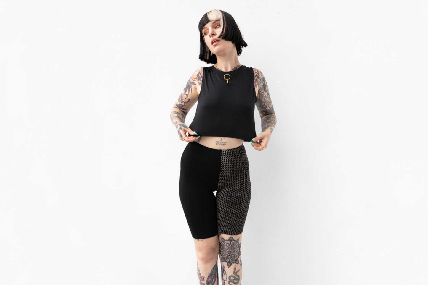 Person trägt asymmetrische Biker Shorts mit abstraktem Ziegelstein-Muster in Schwarz und Beige.