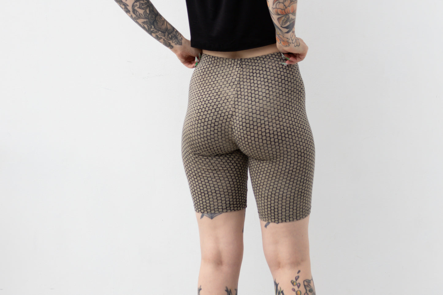 Mid-Waist Biker Shorts mit geometrisch anmutendem Ziegelsteinmuster in Beige und dunkelblauen Farbverläufen, Aufnahme von hinten.