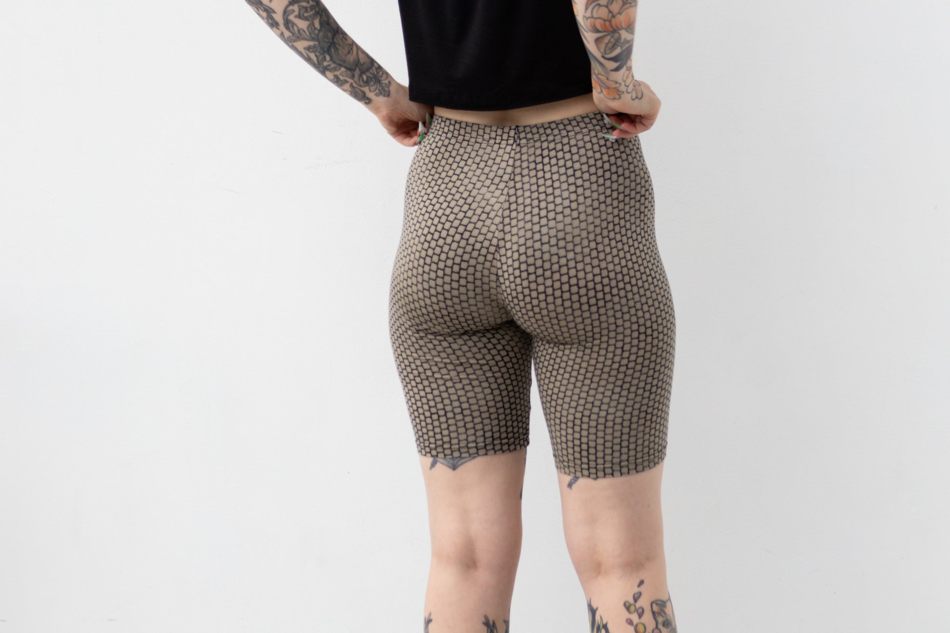 Mid-Waist Biker Shorts mit geometrisch anmutendem Ziegelsteinmuster in Beige und dunkelblauen Farbverläufen, Aufnahme von hinten.