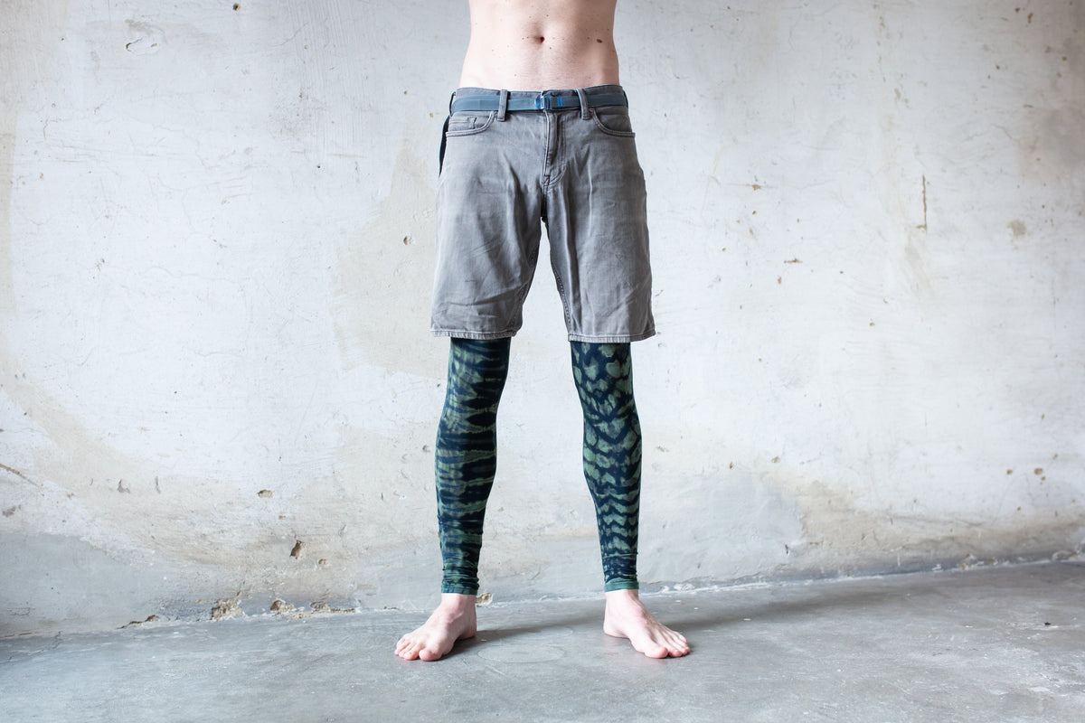 Mann trägt Unisex Batik Leggings mit Leopardenmuster Tierprint dunkelblau-türkis unter kurzer Jeans – Yoga Psytrance Punk