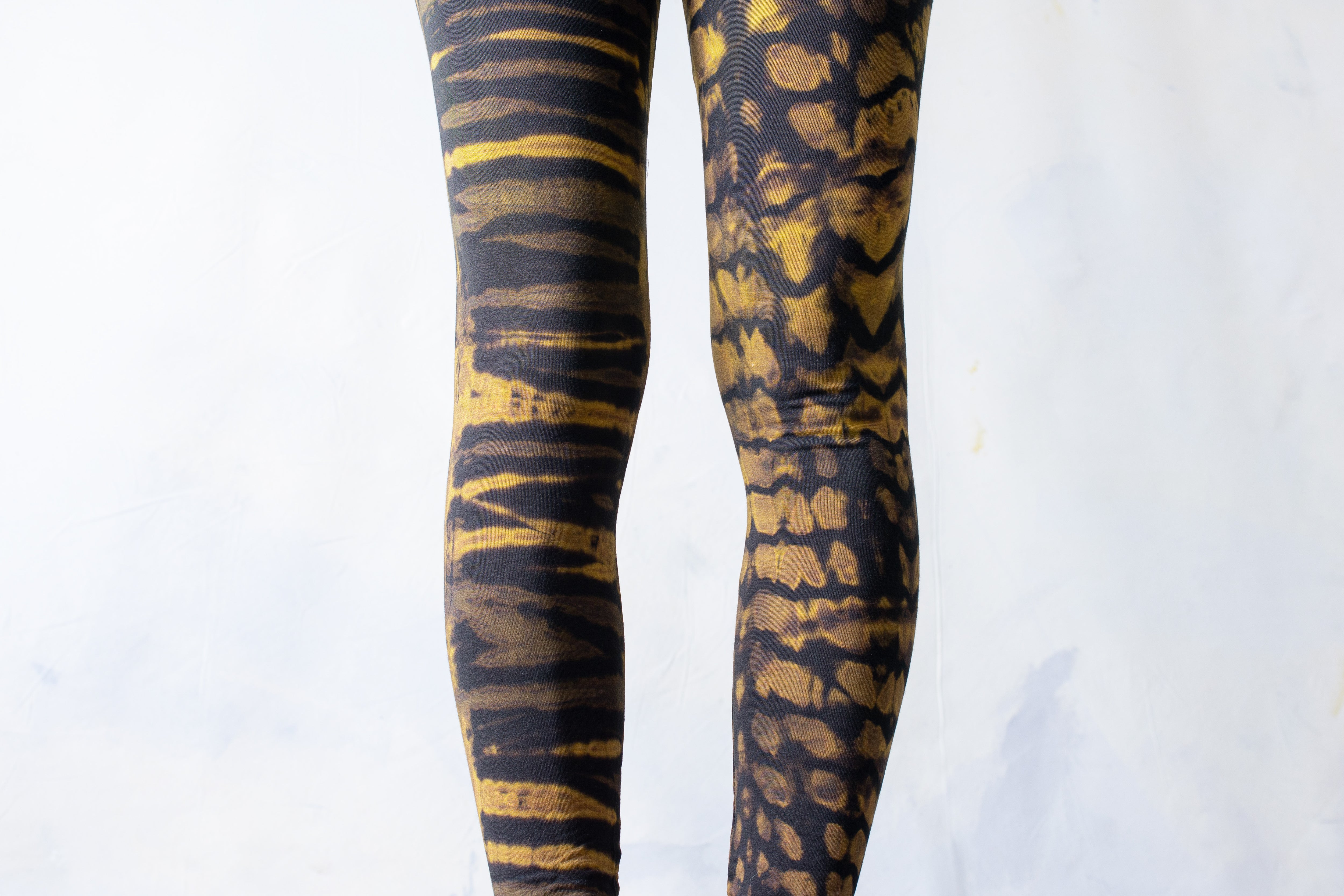Detailaufnahme Tigerprint Batikmuster auf elastischer Unisex Leggings schwarz-beige-gelb – Alt fashion Psytrance Punk Yoga