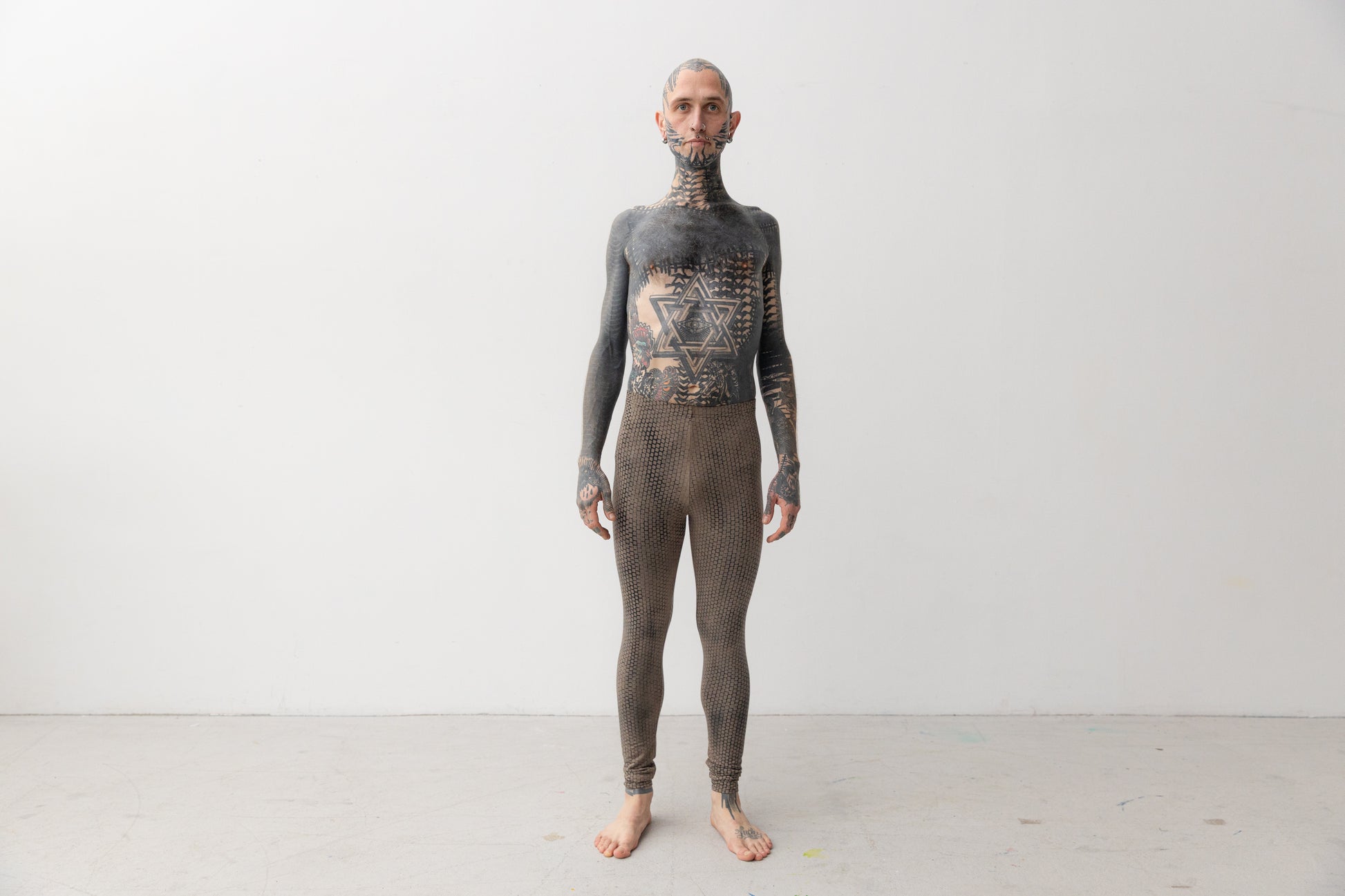 Tätowiertes Model trägt genderneutrale Leggings mit abstraktem Siebdruck-Muster in beige-blau.