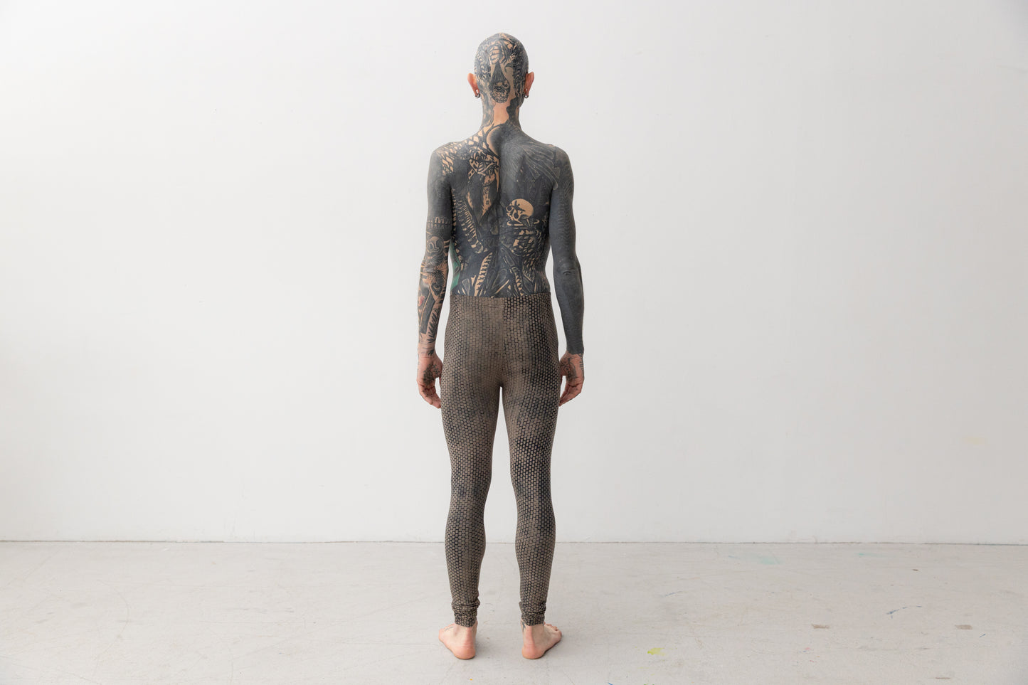 Männlich gelesenes Model trägt Leggings mit abstraktem, geometrischem Muster in indigofarben, Aufnahme von hinten.