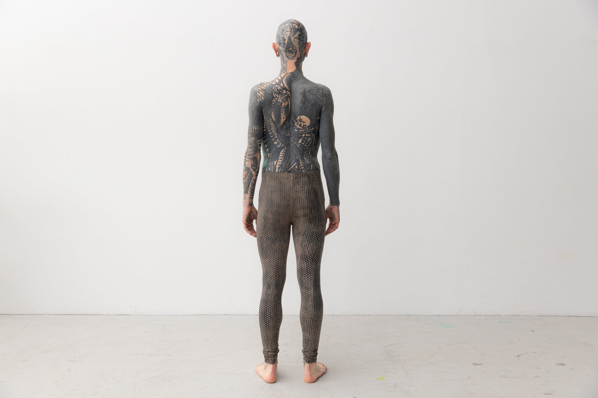 Männlich gelesenes Model trägt Leggings mit abstraktem, geometrischem Muster in indigofarben, Aufnahme von hinten.