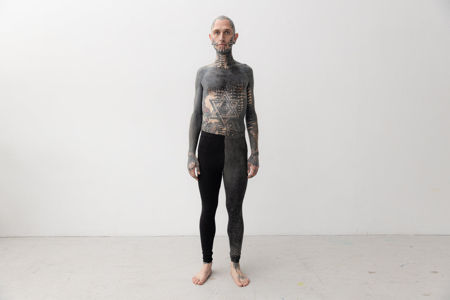 Alternatives Model trägt Leggings mit asymmetrischem Print an einem Bein.