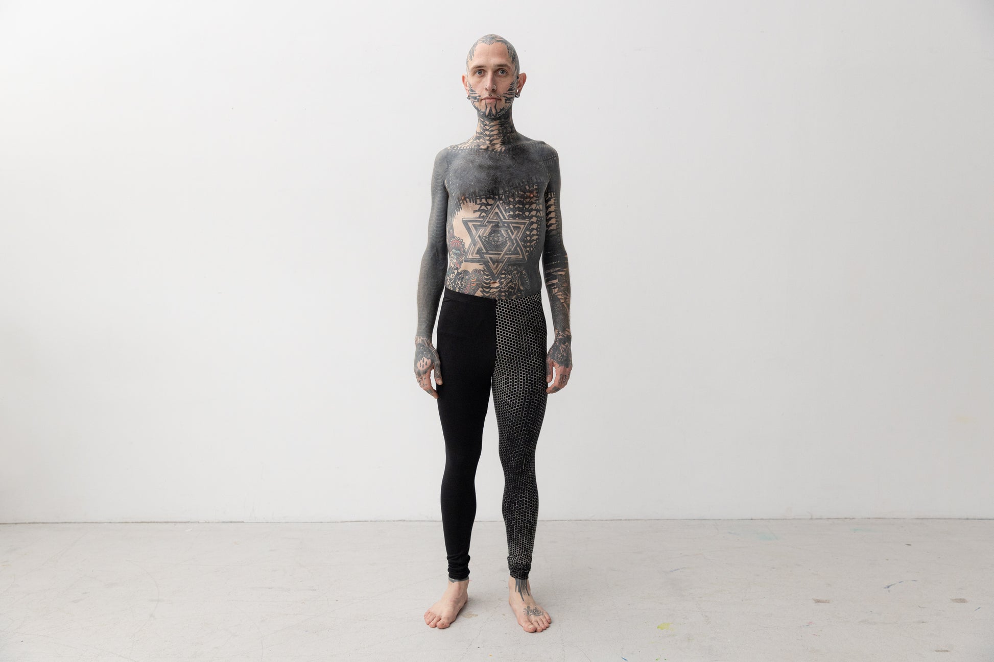 Alternatives Model trägt Leggings mit asymmetrischem Print an einem Bein.