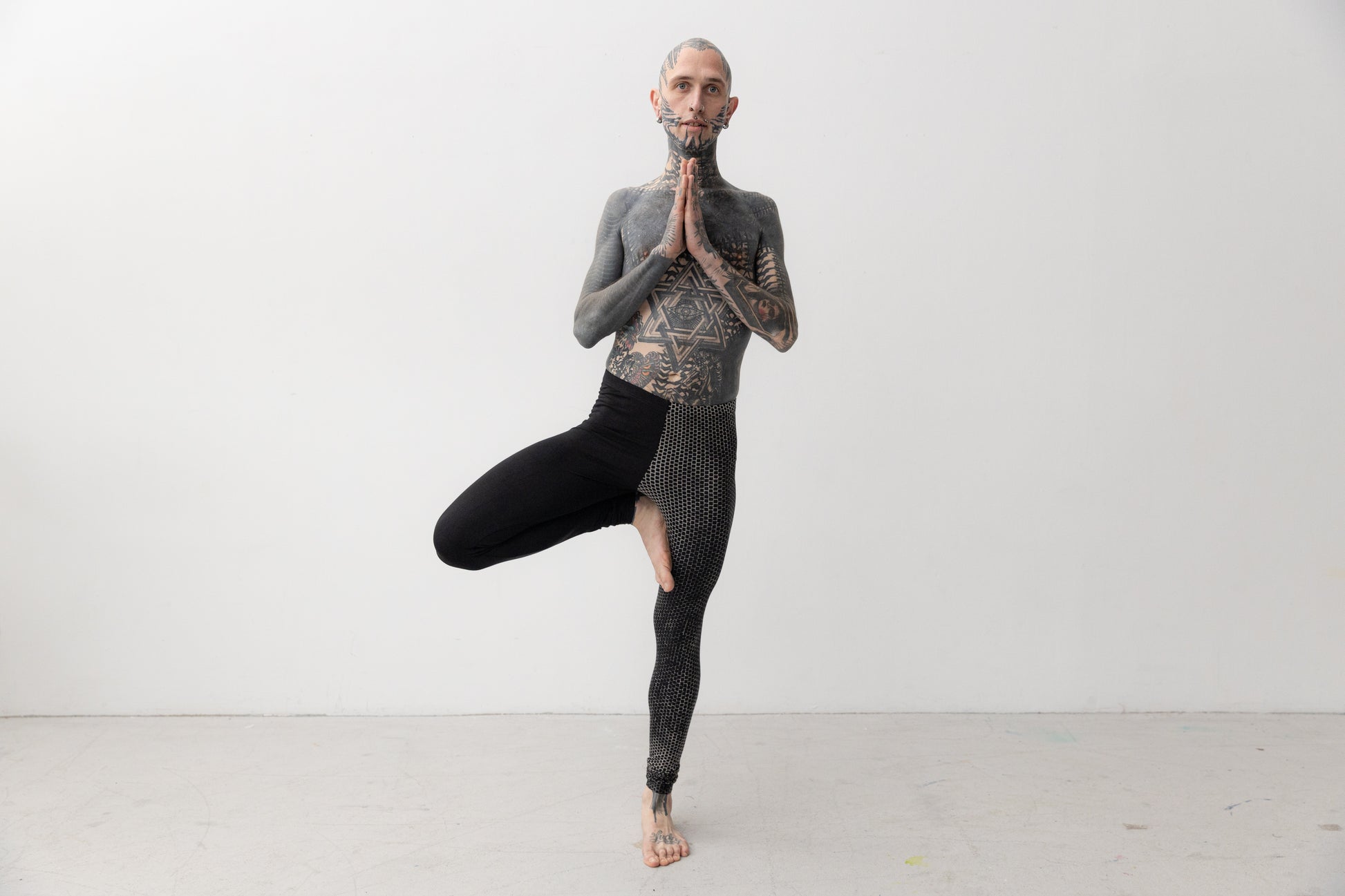 Yoga Pose von männlich gelesenem Model, das Leggings mit asymmetrischem Print trägt.