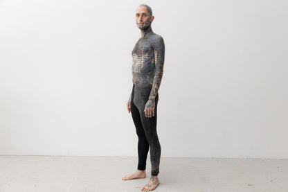 Tätowiertes Model trägt genderneutrale Leggings mit asymmetrischem Print an einem Bein.