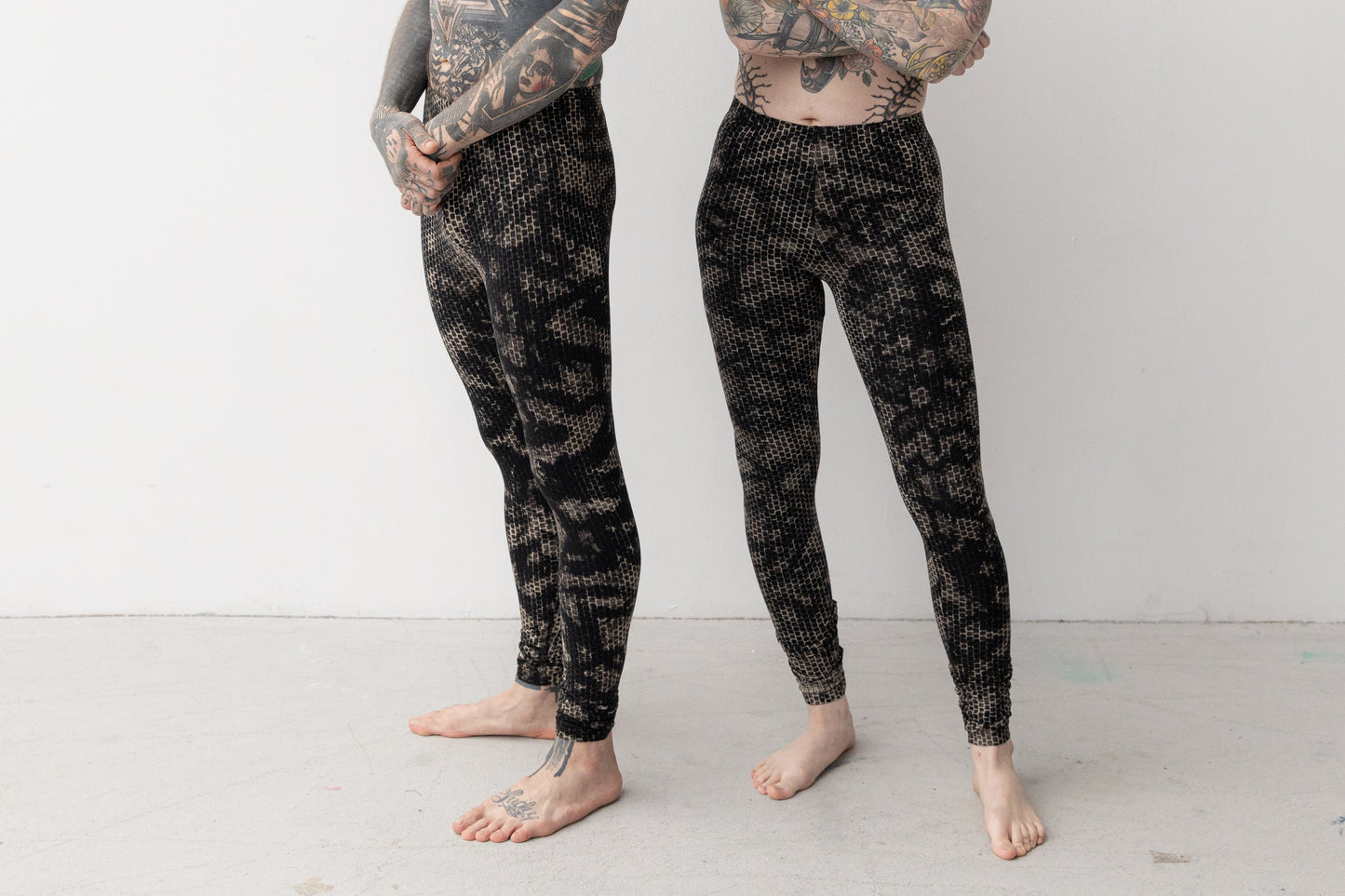 Ausgefallene Leggings mit Batik-Siebdruck Muster in schwarz-beige-grau, getragen an weiblichem und männlichem Model.