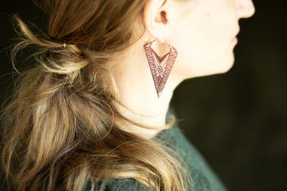 Hoop Ohrringe mit detailliertem geometrischem Muster aus Kupfer und Silber, getragen als auffälliger Boho Statement Schmuck.