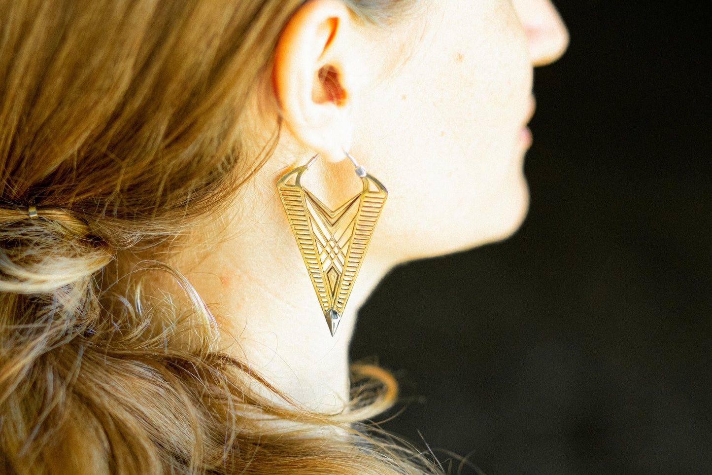 Geometrische Boho Ohrringe getragen am Ohr mit großem Anhänger aus Messing.