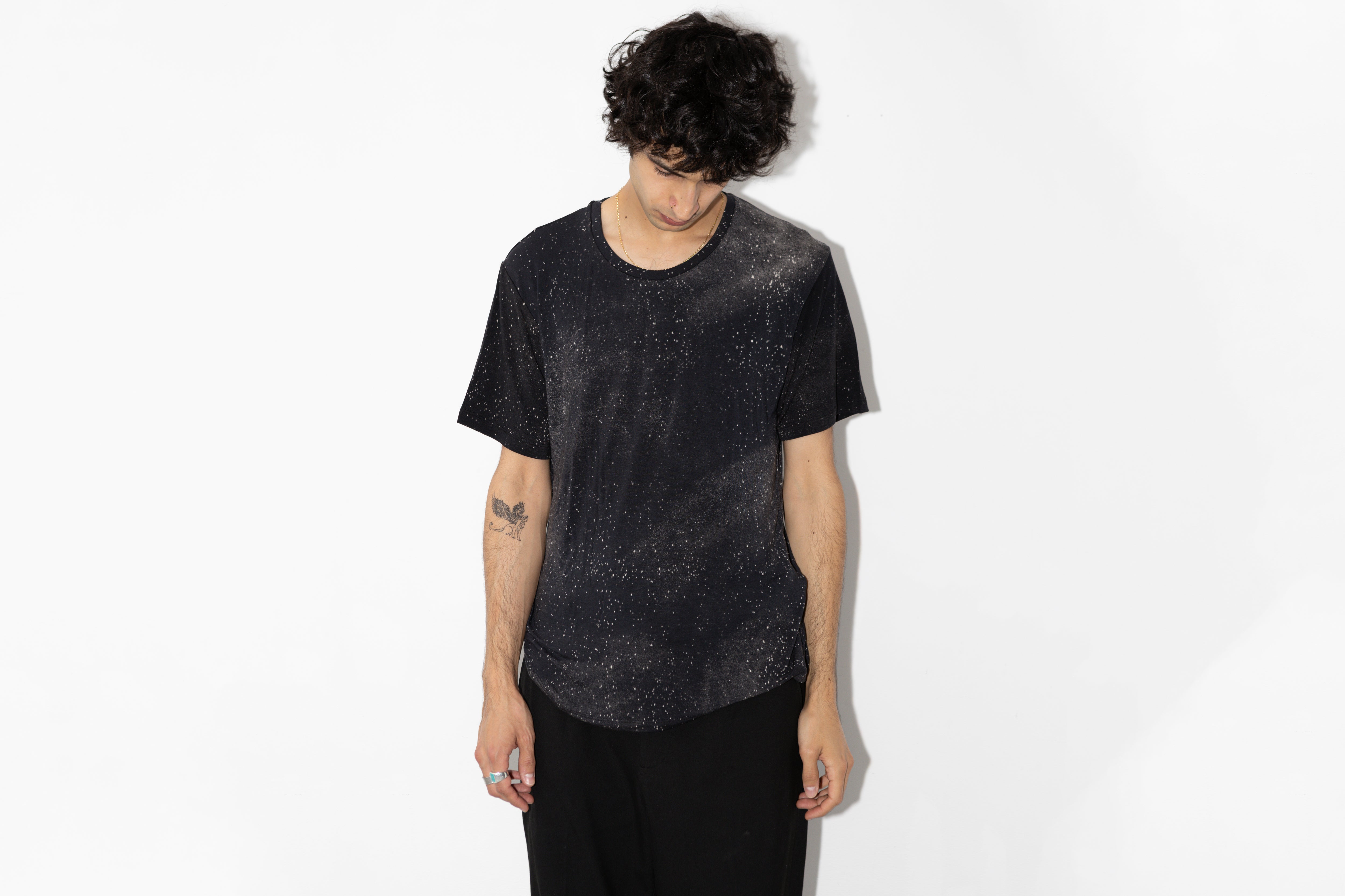 Männlich gelesenes Model trägt dunkelgrau-blaues T-Shirt mit Sternenhimmel Print