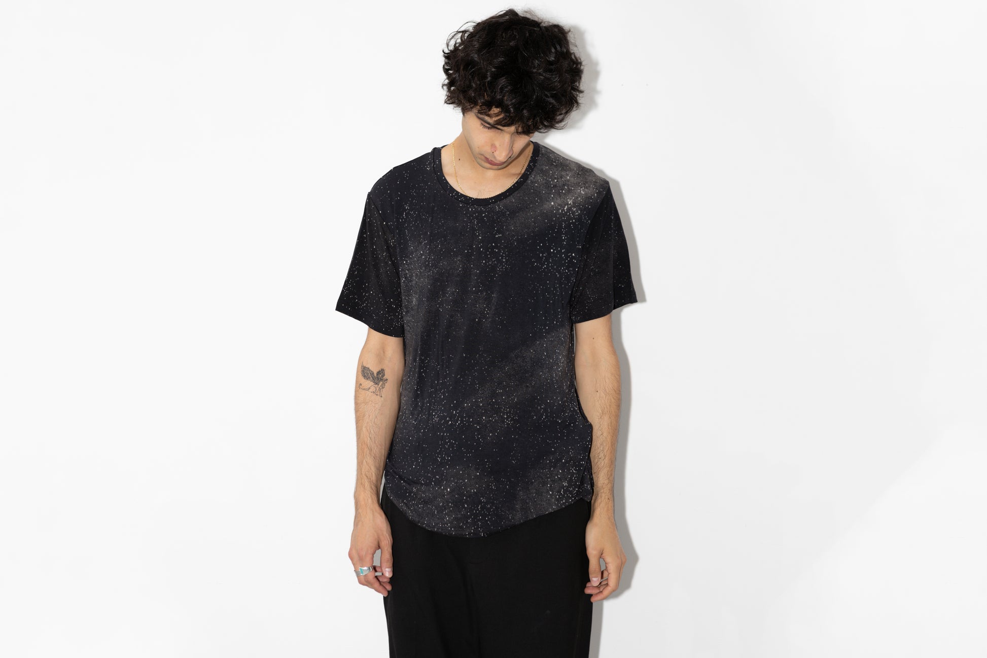 Männlich gelesenes Model trägt dunkelgrau-blaues T-Shirt mit Sternenhimmel Print