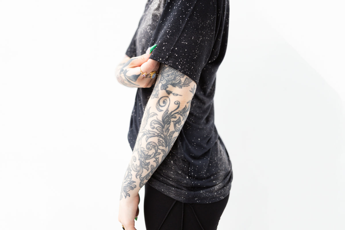 Nahaufnahme Ärmel von T-Shirt mit Batik-Universum-Motiv in dunklem Blau-Grau