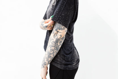 Nahaufnahme Ärmel von T-Shirt mit Batik-Universum-Motiv in dunklem Blau-Grau