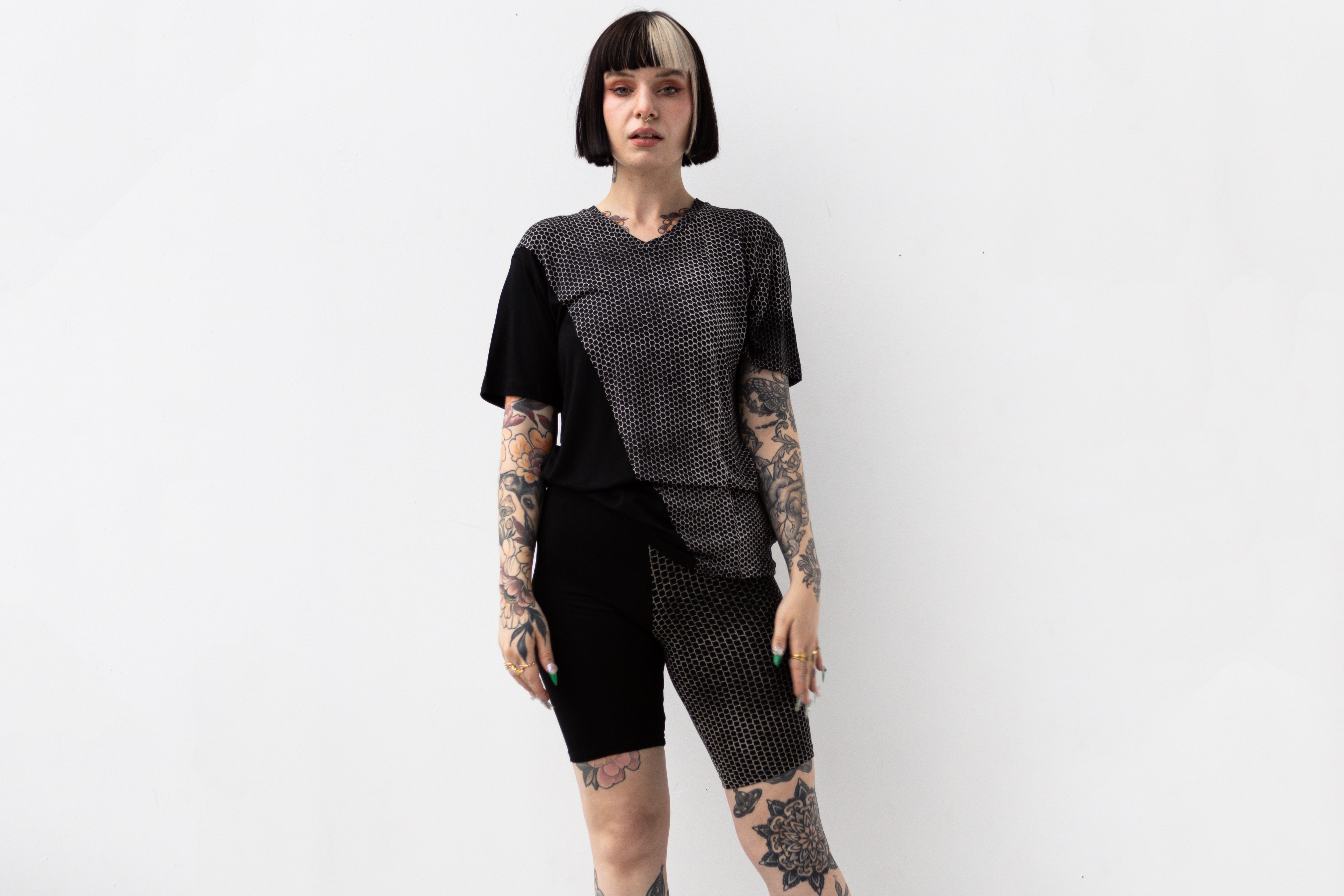 Weiblich gelesenes Model trägt ausgefallenes T-Shirt in schwarz mit beigem Hexagon-Print.