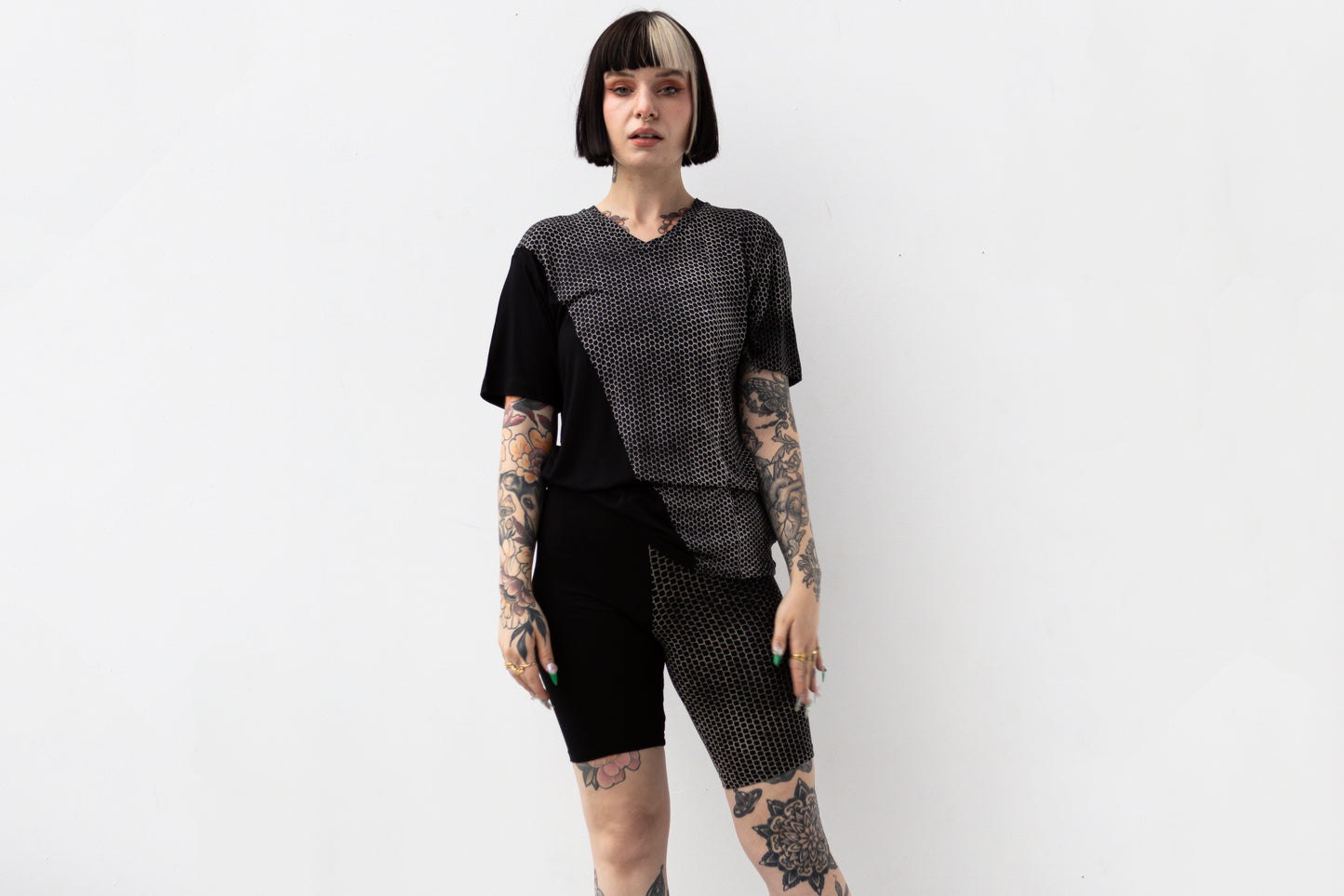 Weiblich gelesenes Model trägt ausgefallenes T-Shirt in schwarz mit beigem Hexagon-Print.