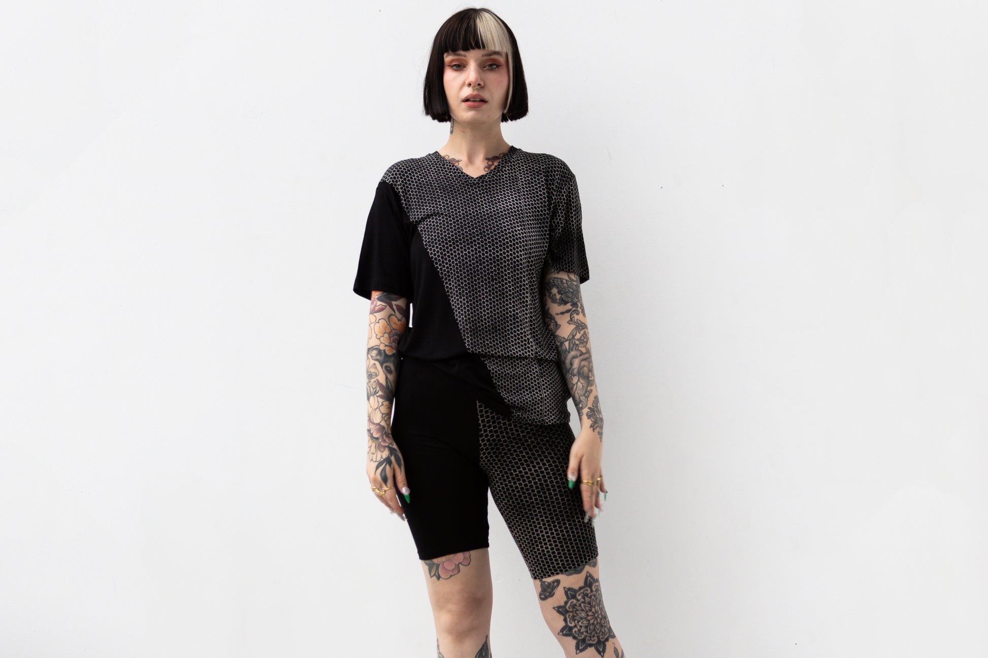 Weiblich gelesenes Model trägt ausgefallenes T-Shirt in schwarz mit beigem Hexagon-Print.