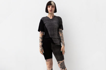 Weiblich gelesenes Model trägt ausgefallenes T-Shirt in schwarz mit beigem Hexagon-Print.