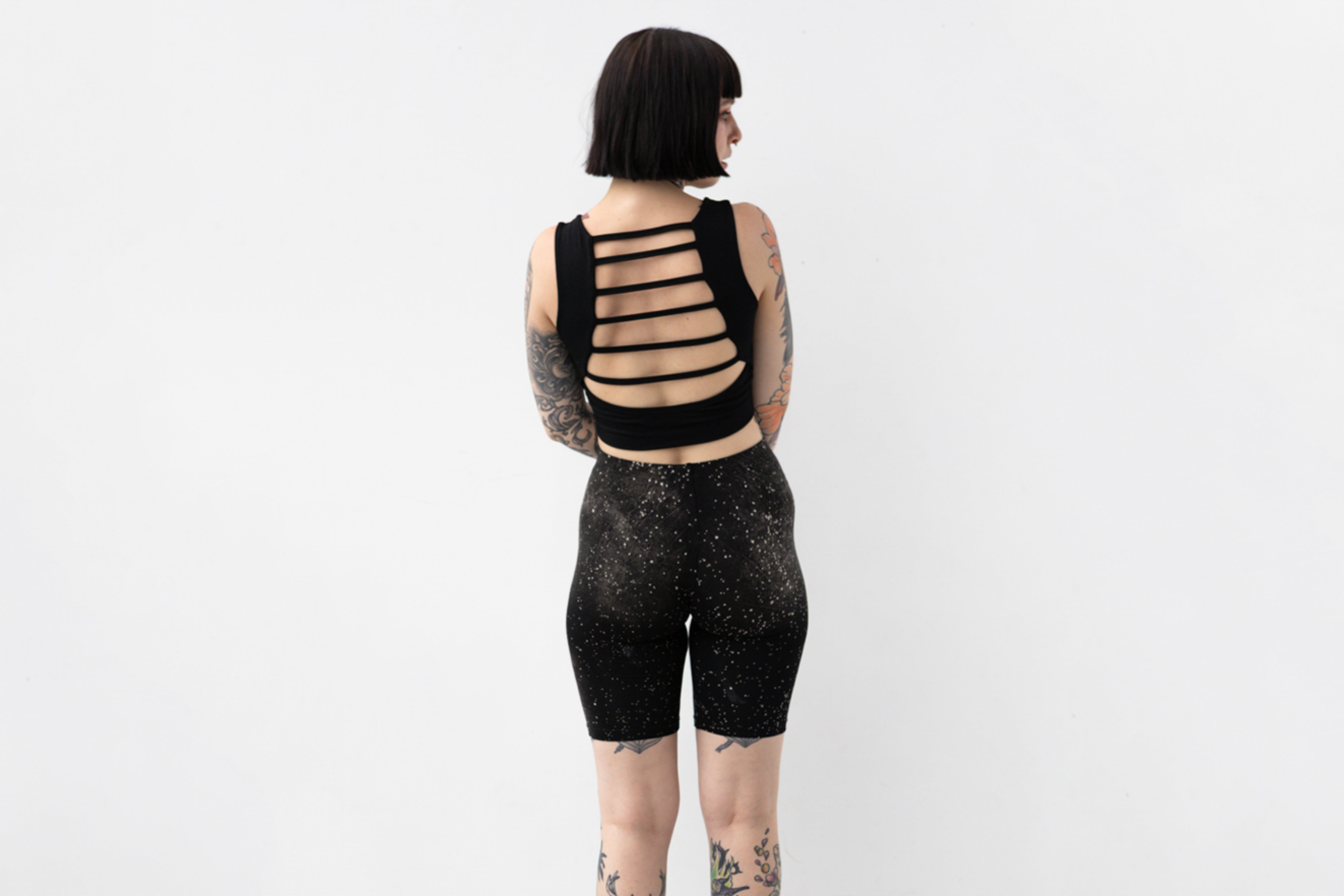 Weiche Yoga Shorts mit abstraktem Galaxie-Print in Grau und Beige auf schwarzem Untergrund, Aufnahme von hinten.