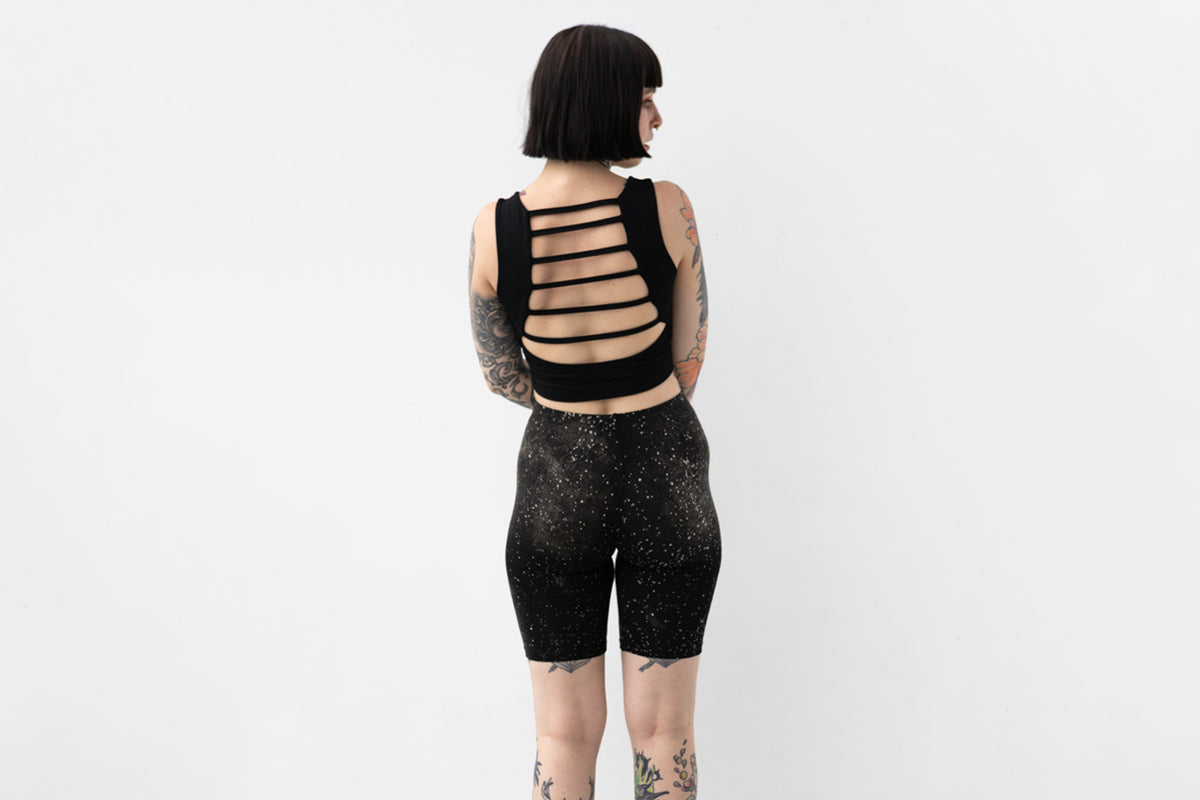 Weiche Yoga Shorts mit abstraktem Galaxie-Print in Grau und Beige auf schwarzem Untergrund, Aufnahme von hinten.