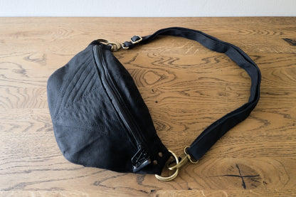 Crossbody-Tasche aus Baumwolle mit Nahtstruktur in schwarz, Gesamtansicht liegend, große Größenvariante L-XL-XXL mit Riemen der an der Enden mit messingfarbenen Karabinerhaken an der Tasche befestigt ist.