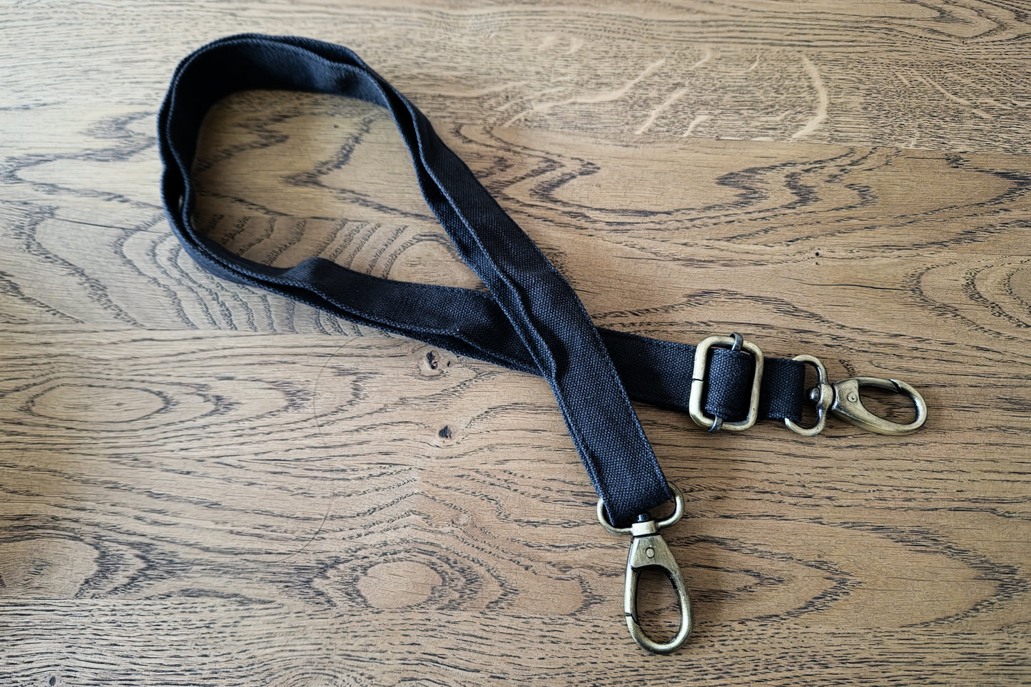 Riemen der großen Größenvariante L-XL-XXL der Crossbody-Tasche mit messingfarbenen Karabinerhaken an der Enden.