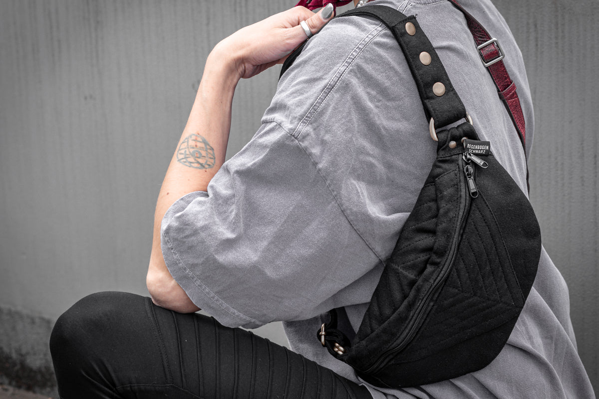 Crossbody-Tasche aus Baumwolle mit Nahtstruktur in schwarz, getragen als Schultertasche.