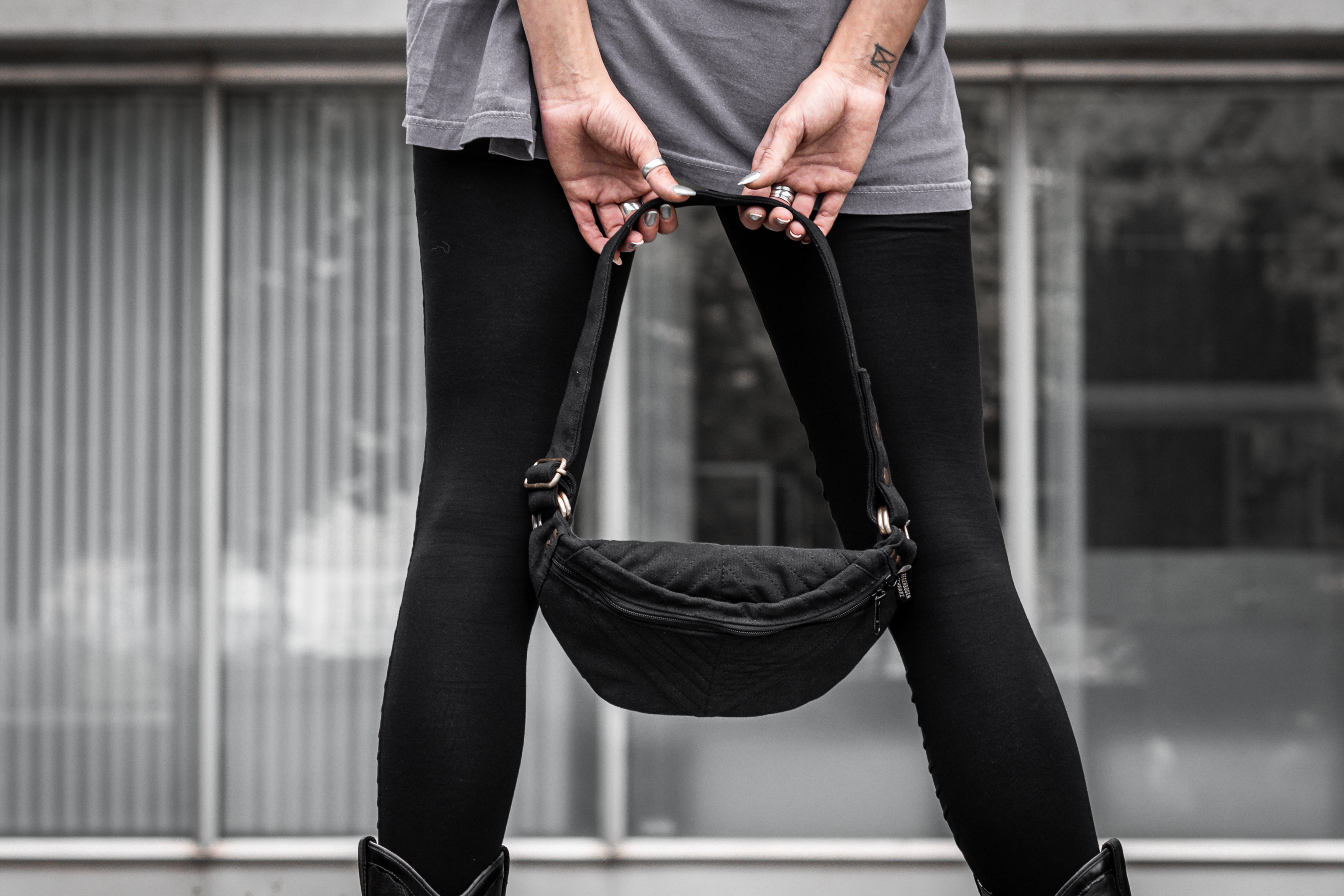 Schwarze crossbody-Tasche aus Baumwolle mit Nahtstruktur und messingfarbenen Details.