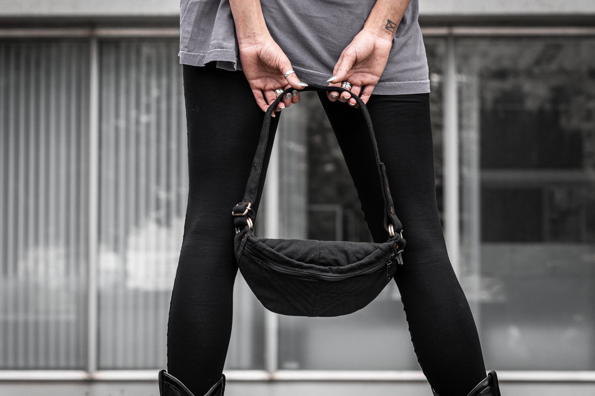 Schwarze crossbody-Tasche aus Baumwolle mit Nahtstruktur und messingfarbenen Details.