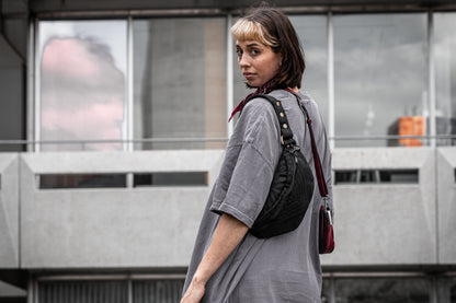 Crossbody-Tasche aus Baumwolle in schwarz, getragen an weiblich gelesenem Model.