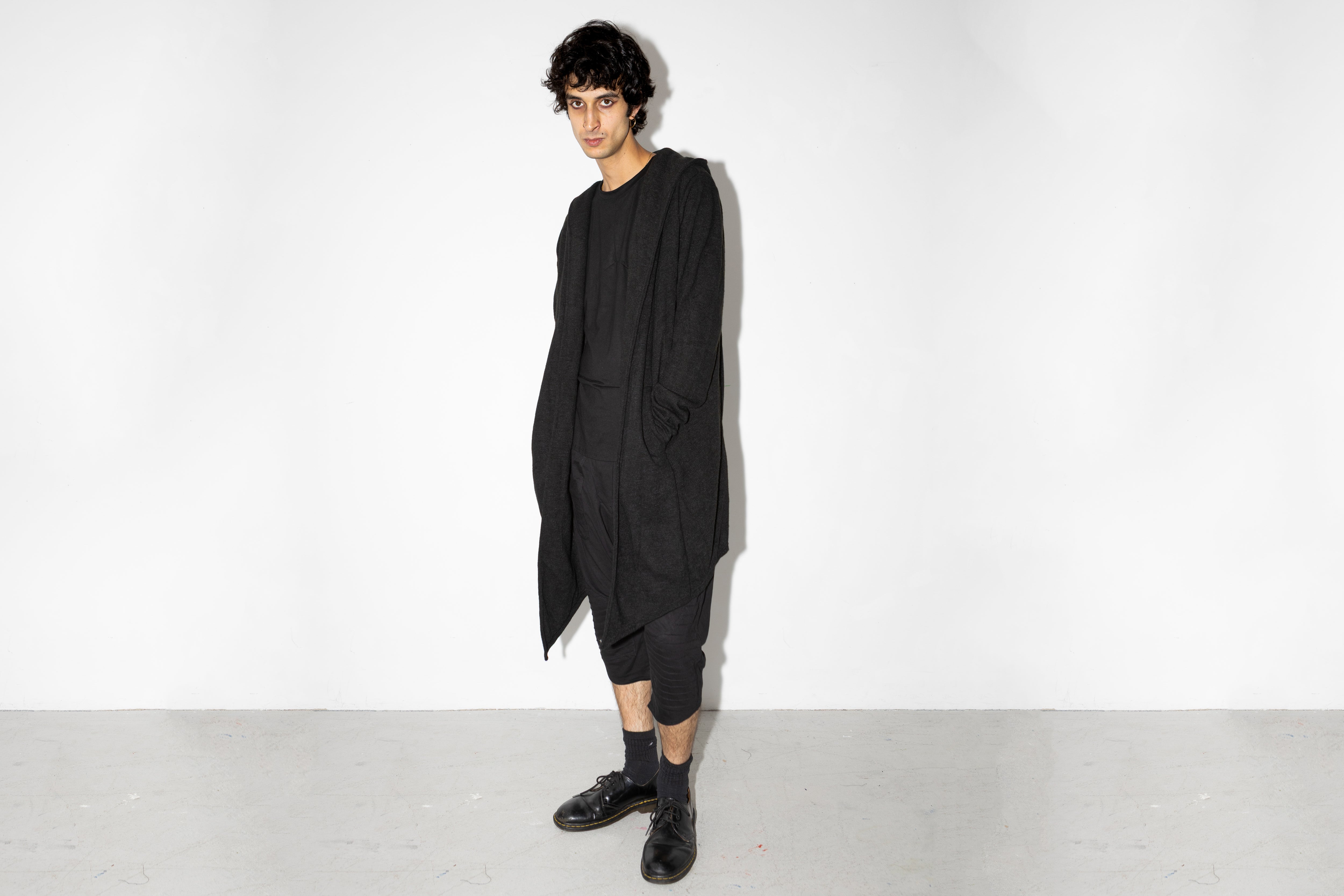 Model trägt langen schwarzen oversized Strickmantel mit Kapuze