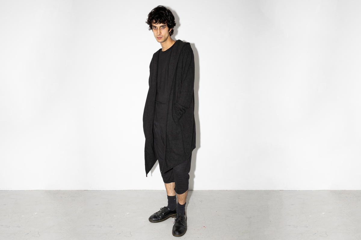 Model trägt langen schwarzen oversized Strickmantel mit Kapuze