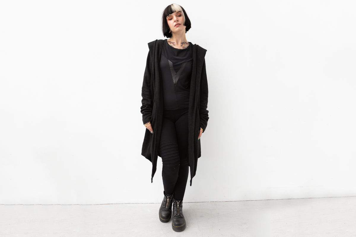 Model trägt schwarzen Kapuzenmantel im Darkwear- und Cyberpunk-Stil, figurumspielender Schnitt, ideal für Herbst und Winter.