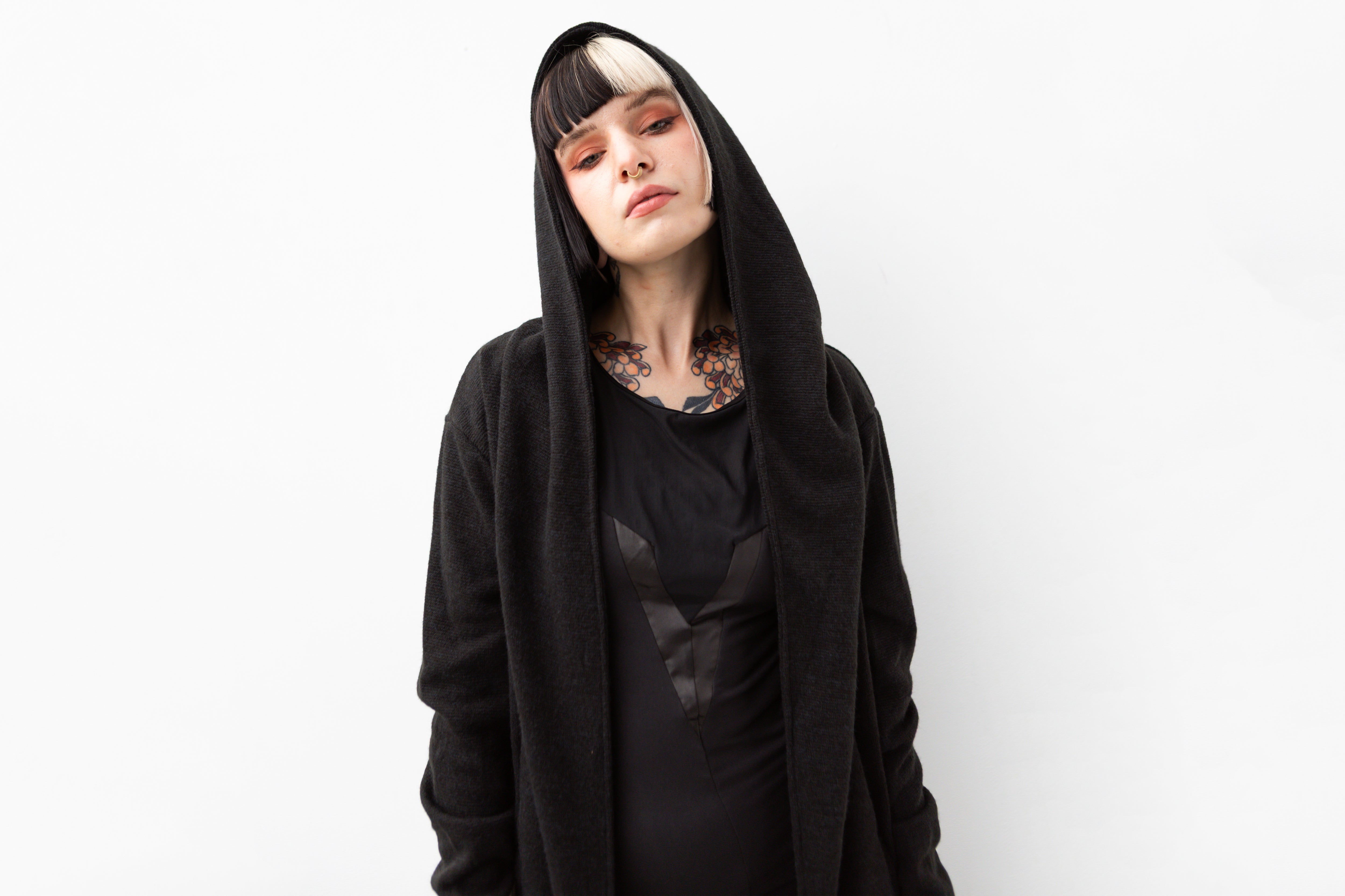 Nahaufnahme eines Models mit schwarzem Kapuzenmantel mit extra großer Kapuze und strukturiertem Material