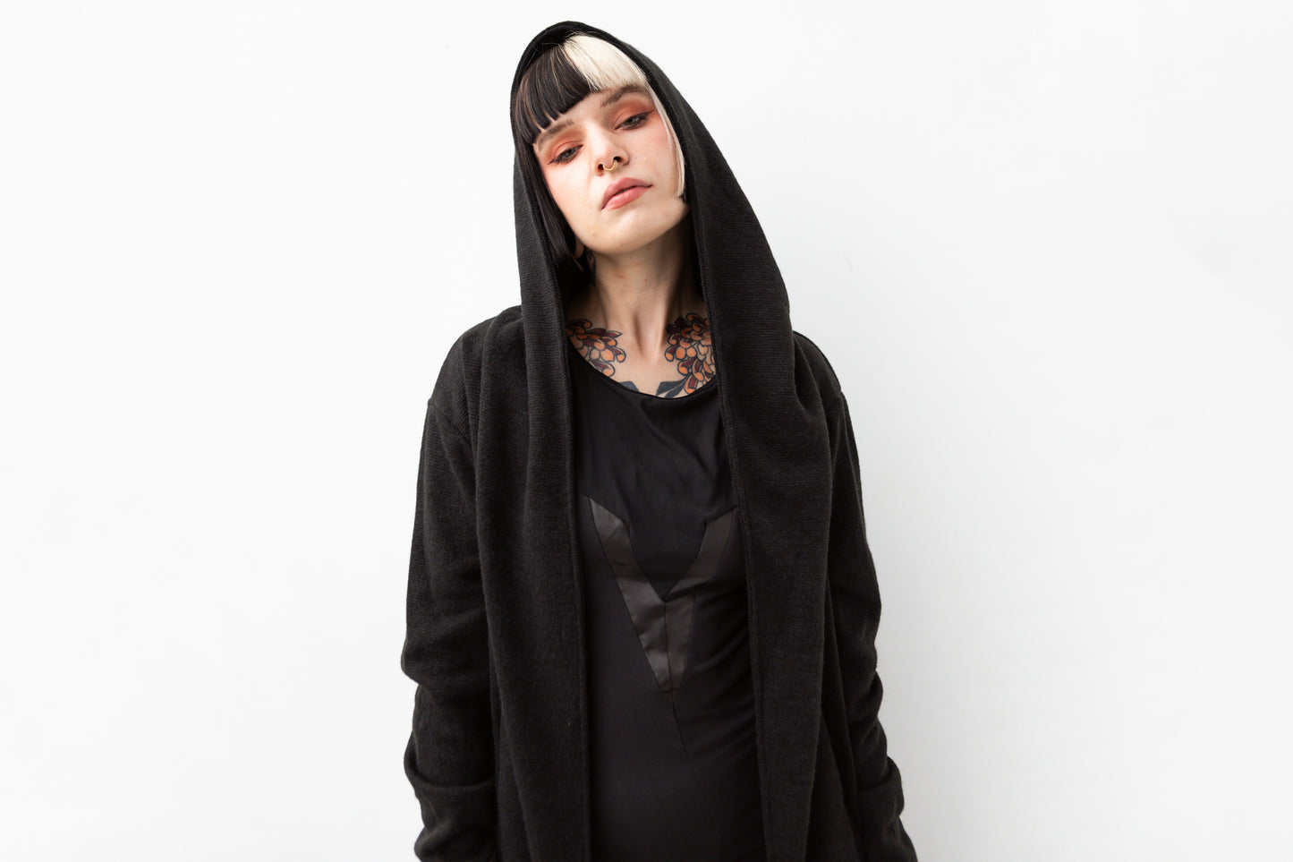 Nahaufnahme von Model mit schwarzem Kapuzenmantel im Goth- und Cyberpunk-Stil, mit extra großer Kapuze und strukturiertem Material.