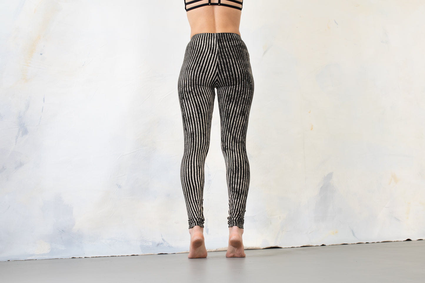 Model trägt schwarz-beige gestreifte Leggings, Aufnahme von hinten.