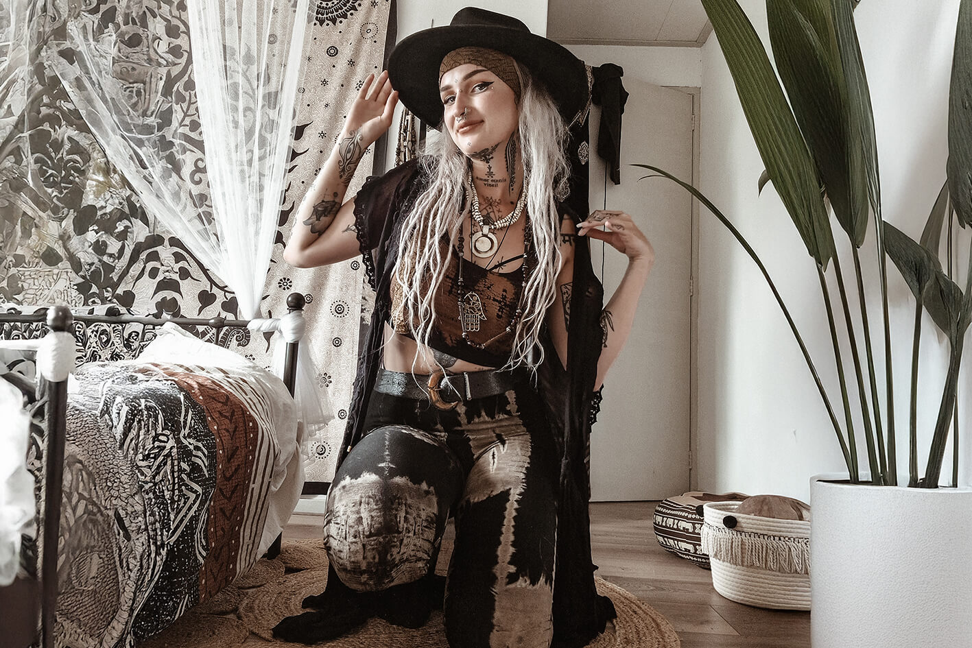 Model in Hocke trägt ein apricotfarbenes Crop-Top mit schwarzen Mustern sowie Leggings mit Batikmuster in Schwarz, Grau und Beige