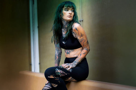 Model trägt schwarzes Bustier mit Racerback-Schnitt und schwarze Leggings mit Cut-Outs und Nieten