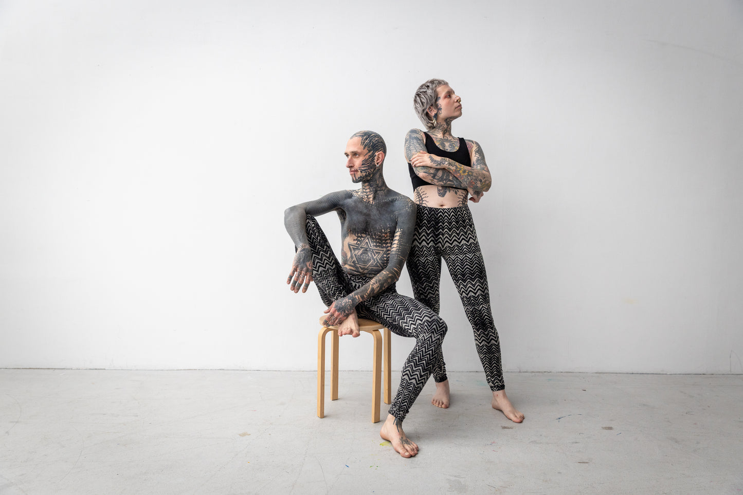 Batik-Leggings mit abstraktem geometrischem Muster in schwarz-beige-grau, getragen an zwei Models, Aufnahme von vorne.