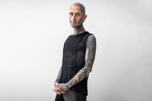 Model trägt schwarzes Netz-Tanktop und asymmetrische Batik Leggings mit Ziegelsteinmuster in beige-grau